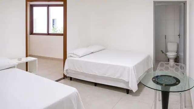 Suíte com camas, mesa e banheiro