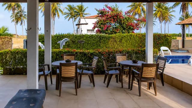 Terraço com mesas, jardim e vista para a piscina